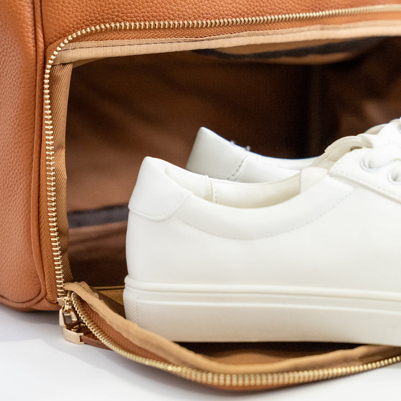 White sneakers inside an open brown leather bag
